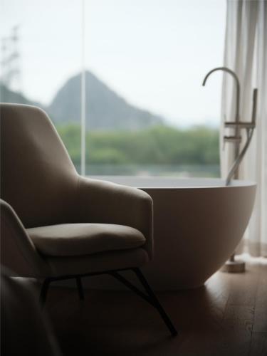 a chair sitting in front of a window with a bathtub at Guilin Bonjour Boutique Hotel- Free pick up service over 3 nights in Guilin