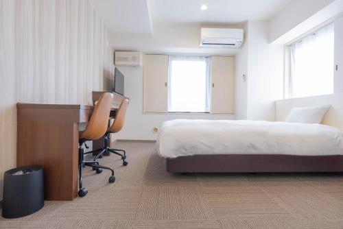 a hotel room with a bed and a desk and a bedskirts at Hotel Alpha Inn Akita in Akita