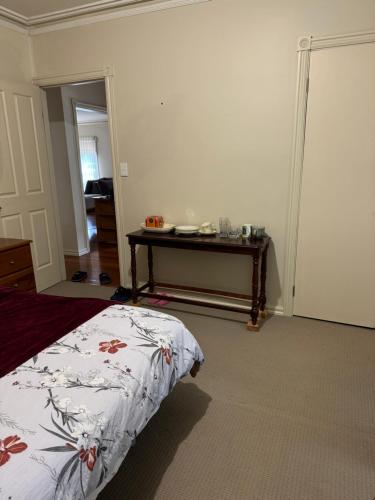 a bedroom with a bed and a table in it at Couple room with shared bathroom in Glen Waverley