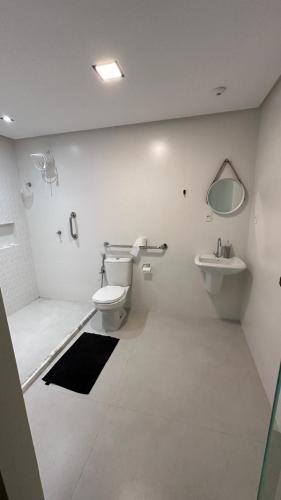a white bathroom with a toilet and a sink at Mansão Moraes - em Itacimirim Linha Verde in Camacari