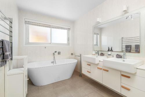 a bathroom with two sinks and a tub and a mirror at Riverleigh, Gerroa in Gerroa
