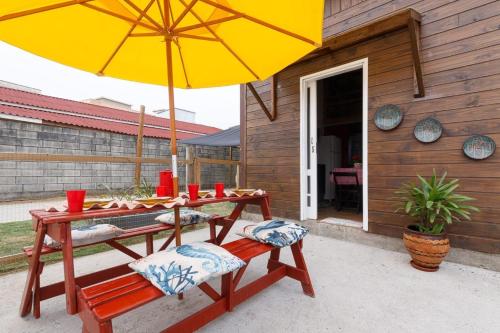 a wooden table with a yellow umbrella and two chairs at Casa Perto das melhores praias Florianópolis, 8 pessoas, ar condicionado, tv, wifi, cozinha completa, lavanderia, in Florianópolis