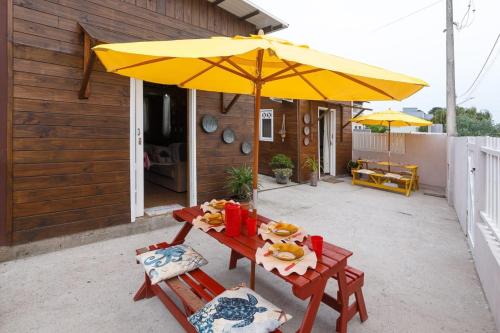 a picnic table with a yellow umbrella on a patio at Casa Perto das melhores praias Florianópolis, 8 pessoas, ar condicionado, tv, wifi, cozinha completa, lavanderia, in Florianópolis