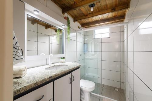 a bathroom with a sink and a toilet and a mirror at Casa Perto das melhores praias Florianópolis, 8 pessoas, ar condicionado, tv, wifi, cozinha completa, lavanderia, in Florianópolis