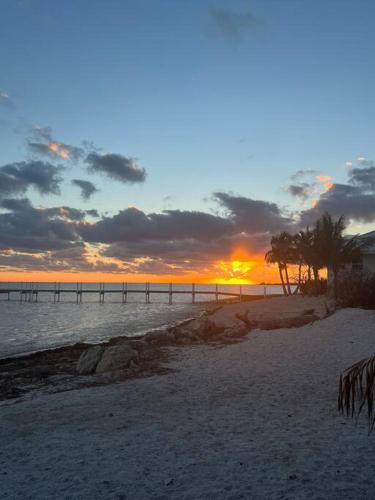 a sunset on a beach with a pier in the water at Beach View Room at Barnacle Resort in Big Pine Key