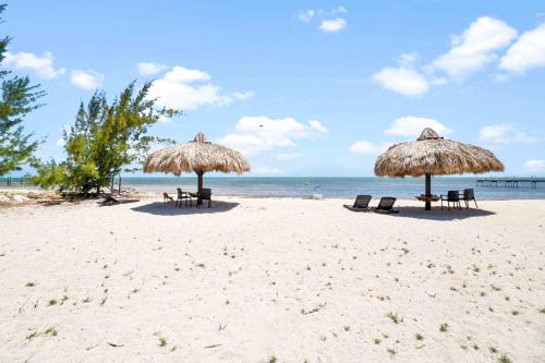 two straw umbrellas and chairs on a beach at Beach View Room at Barnacle Resort in Big Pine Key