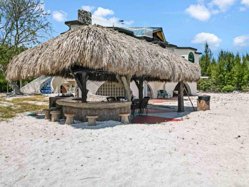 a straw hut on the beach with chairs and a table at Star Room at Barnacle Resort in Big Pine Key