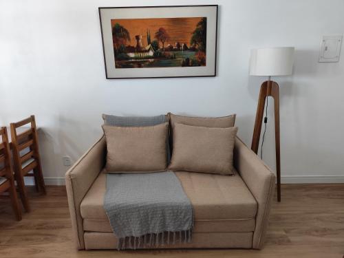 a couch in a living room with a picture on the wall at Apartamento a 500 metros da Praia do Forte in Cabo Frio