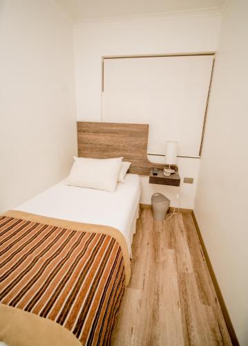 a small bedroom with a bed and a mirror at Hotel Terra Iquique in Iquique
