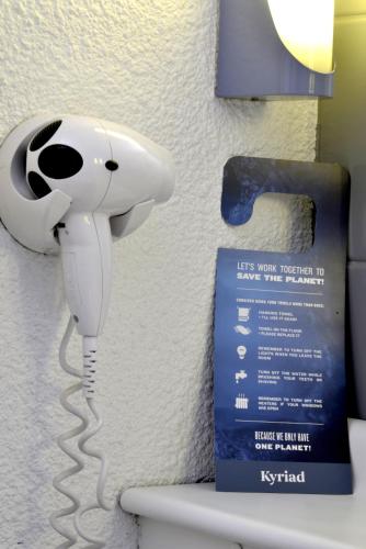 a white hair dryer hanging on a bathroom wall at Kyriad Rouen Sud - Oissel in Saint-Étienne-du-Rouvray
