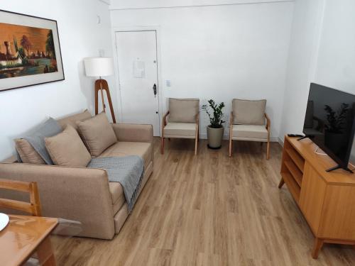a living room with a couch and a tv at Apartamento a 500 metros da Praia do Forte in Cabo Frio