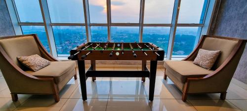 a table and two chairs in a room with a large window at Apt Roseville Soho BSD 1 BR Mezzanine with Netflix & Pool by Damaresa in Dadap