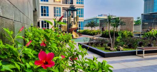 DadapApt Roseville Soho BSD 1 BR Mezzanine with Netflix & Pool by Damaresa的一座花园,里面设有滑梯和鲜花