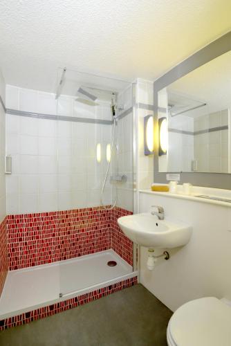 a bathroom with a sink and a toilet and a mirror at Kyriad Rouen Sud - Oissel in Saint-Étienne-du-Rouvray