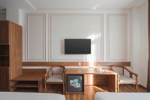 a living room with a tv and a table and chairs at Dalat Roof Hotel in Da Lat
