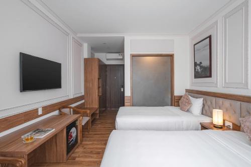 a hotel room with two beds and a flat screen tv at Dalat Roof Hotel in Da Lat