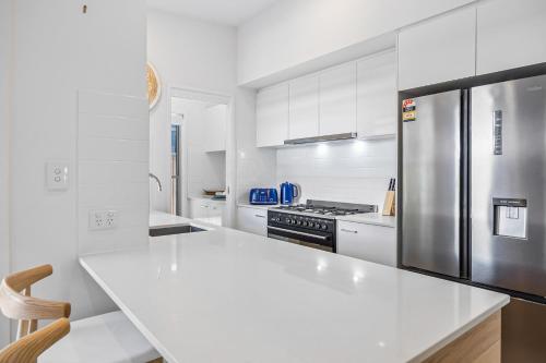 a white kitchen with a stainless steel refrigerator at Premium 4-Bed Coastal Escape with BBQ and Pool in Peregian Beach