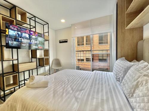 una camera da letto con un grande letto bianco e una TV di Loft ONCE-94 a Bogotá