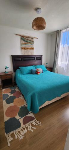 a bedroom with a large bed with a blue blanket at Cond Bahia Pelicano in Puchuncaví