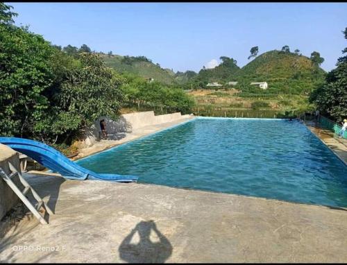 a swimming pool with a blue recliner in the middle at Y Sao Homestay in Hòa Bình