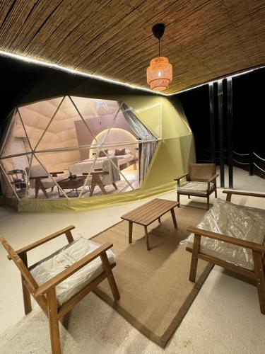 Al RakaにあるSunset domes private campのテント内のベンチとテーブル付きの部屋