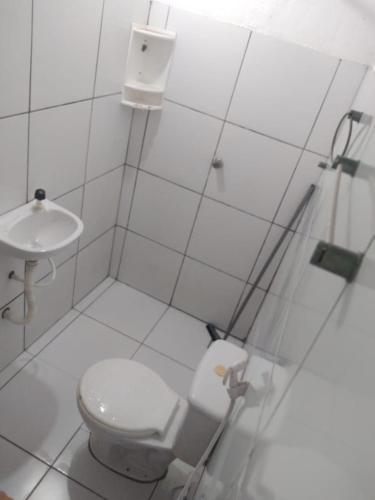 a white bathroom with a toilet and a sink at Casa de praia in Luis Correia