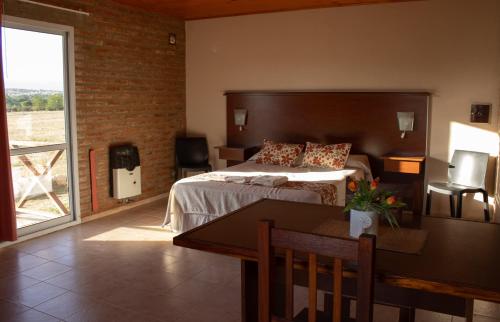 a bedroom with a bed and a table and a dining room at Complejo de cabañas- Lomas del Sol in Los Reartes