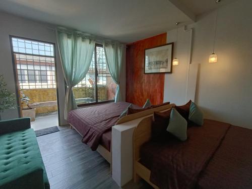 a bedroom with a bed and a couch and windows at Grey Brown Green house at chiangmai old town in Chiang Mai