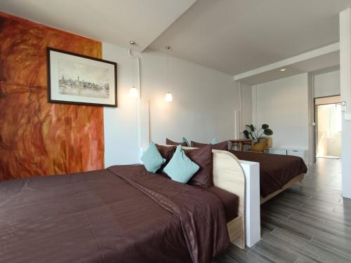 ein Schlafzimmer mit einem großen Bett mit brauner Bettwäsche und blauen Kissen in der Unterkunft Grey Brown Green house at chiangmai old town in Chiang Mai