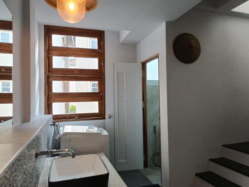 ein Badezimmer mit Waschbecken und Toilette und einem Fenster in der Unterkunft Grey Brown Green house at chiangmai old town in Chiang Mai