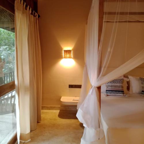 a bedroom with a canopy bed with a window at Casa Vana Hiriketiya in Hiriketiya