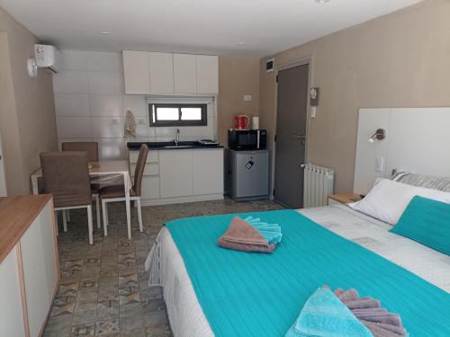 a bedroom with a large bed and a kitchen at Departamento La Delfina in Ciudad Lujan de Cuyo