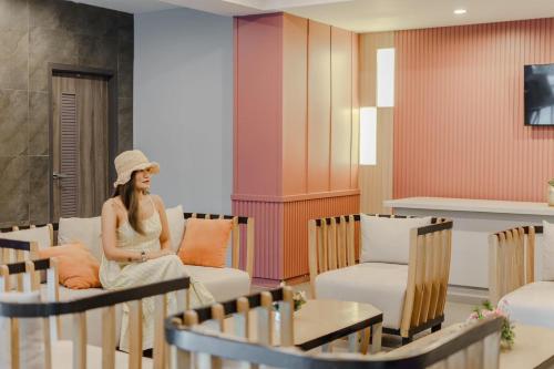 a woman sitting on a couch in a room at Lima Hotel in Phra Nakhon Si Ayutthaya