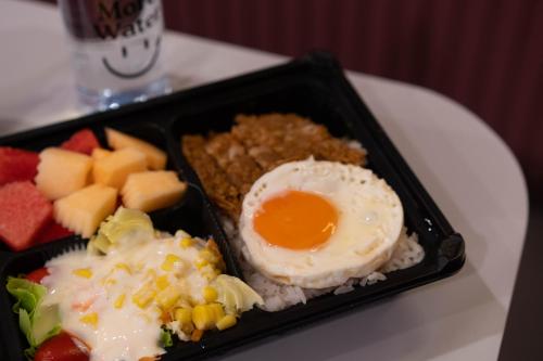 a black container of food with an egg and fruit at Lima Hotel in Phra Nakhon Si Ayutthaya