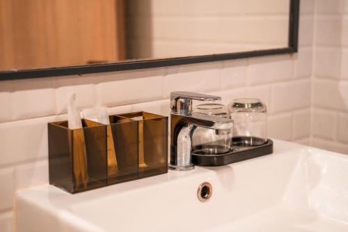 a bathroom sink with a faucet and a mirror at Lima Hotel in Phra Nakhon Si Ayutthaya
