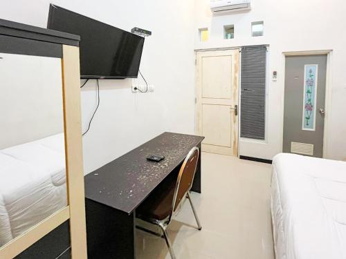 a room with a bed and a desk in a room at Oma Kost 3 Probolinggo Mitra RedDoorz in Probolinggo