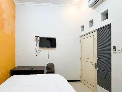 a bedroom with a bed and a tv on a wall at Oma Kost 3 Probolinggo Mitra RedDoorz in Probolinggo