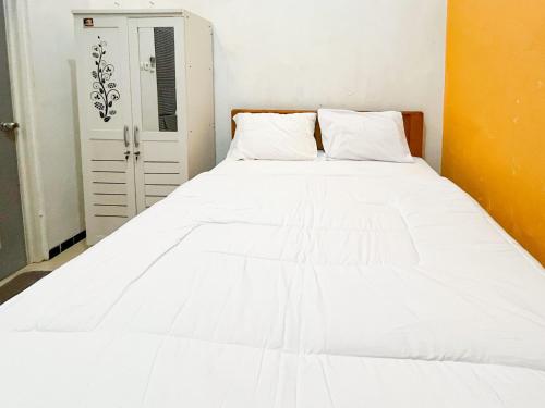 a large white bed with two pillows on it at Oma Kost 3 Probolinggo Mitra RedDoorz in Probolinggo