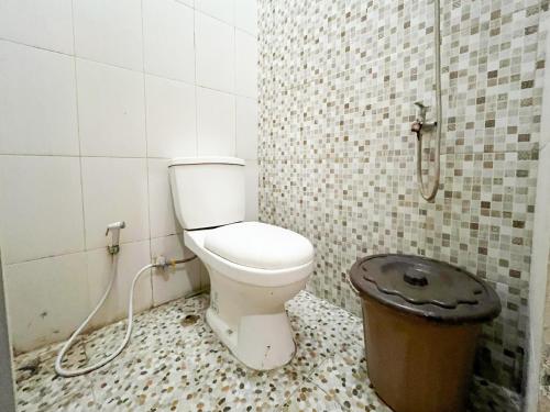 a bathroom with a toilet and a trash can at Oma Kost 3 Probolinggo Mitra RedDoorz in Probolinggo