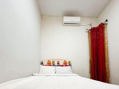 a bedroom with a bed with a red curtain at Oma Kost 3 Probolinggo Mitra RedDoorz in Probolinggo