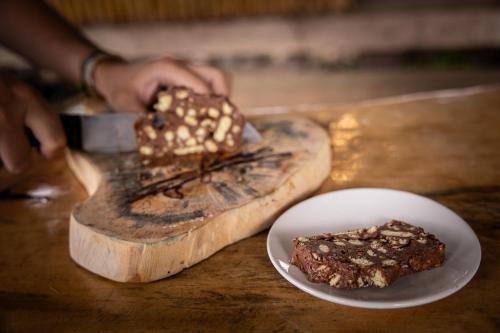 a person cutting a piece of cake on a table with a plate at Gaarawe, Khao Sok, Surat Thani Province, Thailande in Ban Bencha