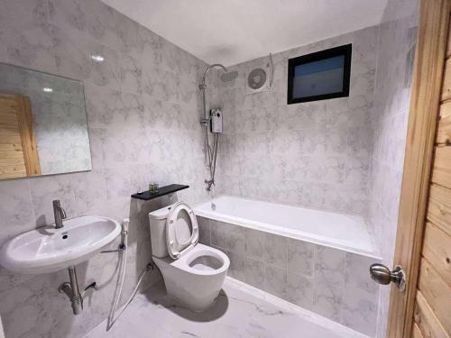 a bathroom with a toilet and a sink and a tub at จอมเมือง Motel in Nan