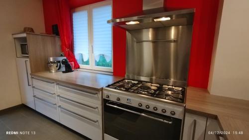 d'une cuisine avec une cuisinière en acier inoxydable et des murs rouges. dans l'établissement La Renardière, à Labaroche