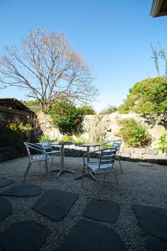 two chairs and a table in front of a stone wall at Jahayeon Hanokstay in Jeonju