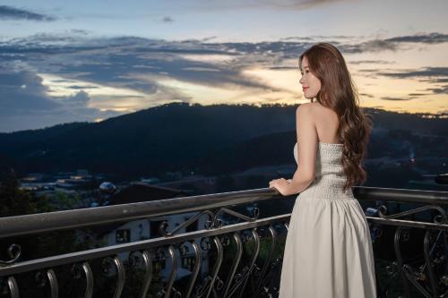 a woman in a white dress standing on a balcony at Dalat Roof Hotel in Da Lat