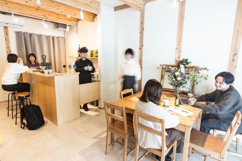 a group of people sitting at tables in a restaurant at Fukuoka Guesthouse CAMP in Fukuoka