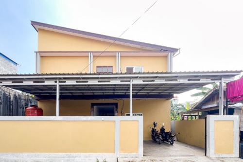 a yellow house with motorcycles parked in front of it at Good Sleep 4 RedPartner in Samarinda