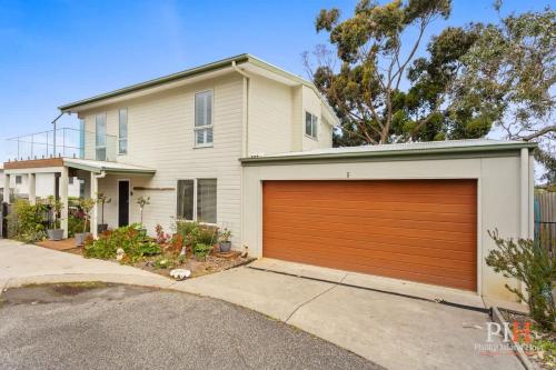 a white house with a brown garage door at Tranquil Holiday Retreat Rhyll in Rhyll