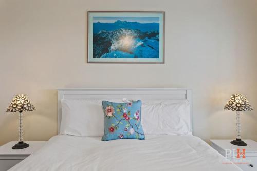a bedroom with a white bed and two lamps at Tranquil Holiday Retreat Rhyll in Rhyll