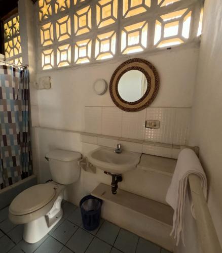 a bathroom with a toilet and a sink and a mirror at La Perla Hostel and Cabins in Las Tunas